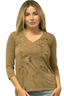  Woman wearing a brown long-sleeve top with floral embroidery on a plain background