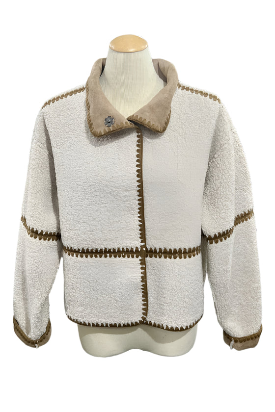 White jacket with brown trim on a mannequin in a store setting