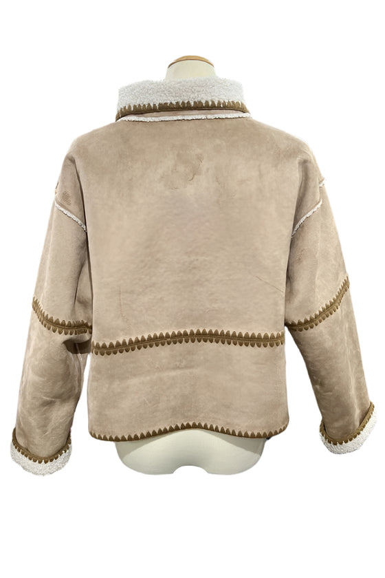 Beige jacket with brown trim on a mannequin in a store setting