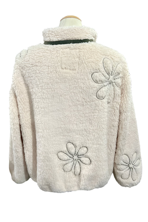 Beige fleece jacket with floral patterns on a mannequin against a blurred indoor background