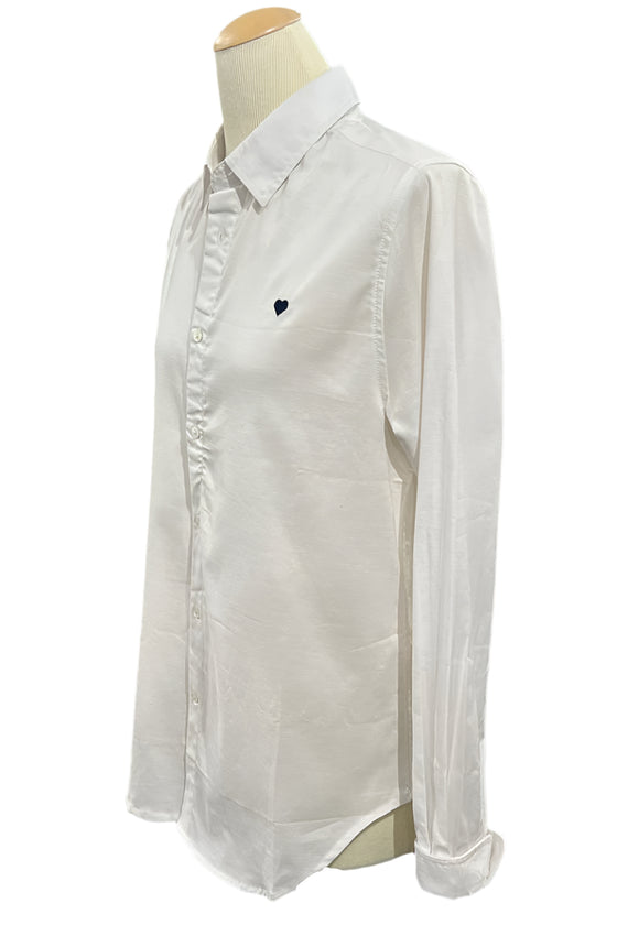 White shirt on a mannequin in an indoor setting with shelves and items in the background