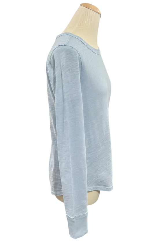 Light blue long-sleeve shirt on a mannequin with a person sitting in the background.