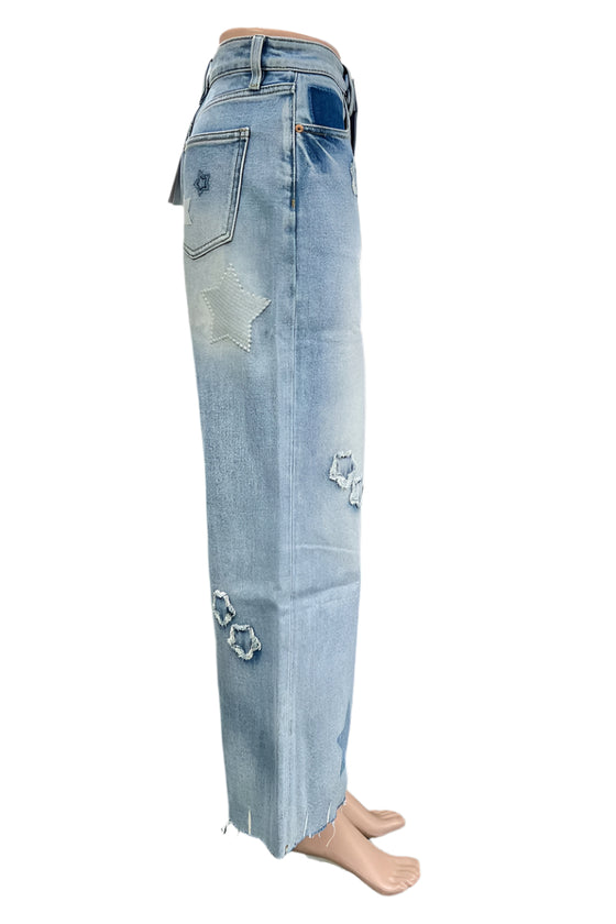 Light blue jeans with star designs worn by a person in a kitchen setting.
