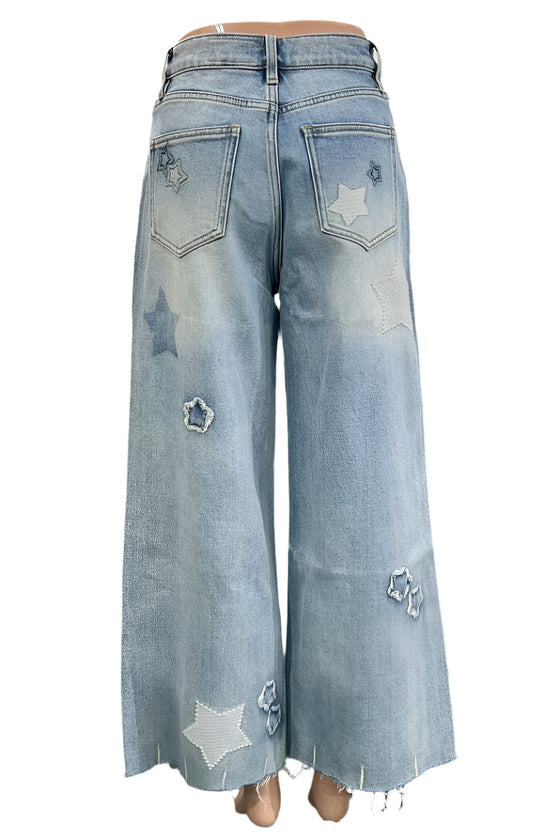 Light blue jeans with star patterns worn by a person in an indoor setting.