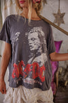 Person wearing a t-shirt with a graphic design of a face and text, standing in a room with a star decoration.