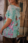 Person wearing a floral-patterned shirt with text on the back, standing indoors.