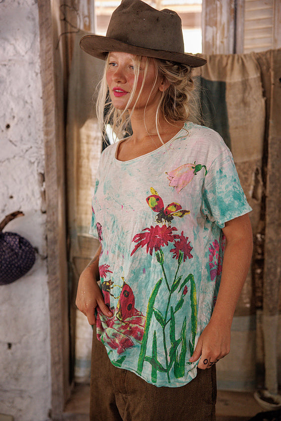 Person wearing a floral t-shirt and brown hat in an indoor setting