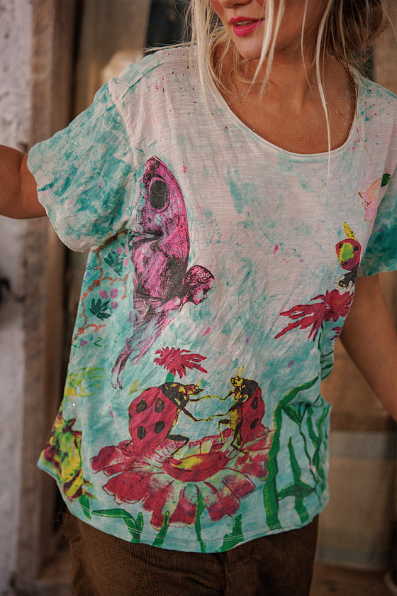 Person wearing a colorful t-shirt with artistic designs and text.