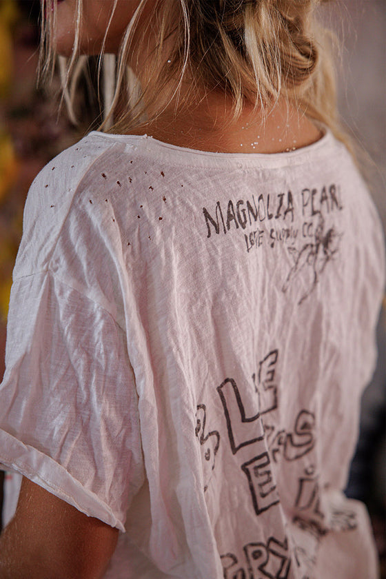 White t-shirt with text and graphics on the back worn by a person.