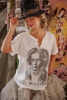  Woman wearing a white t-shirt with a graphic design, standing in front of a colorful mural.
