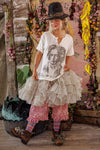 Person wearing a white t-shirt with a graphic design, ruffled skirt, and colorful socks in a decorative setting.