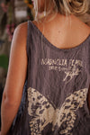 Person wearing a tank top with 'Magnolia Pearl' branding and butterfly design.