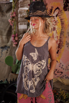  Woman wearing a tank top with butterfly design and pink pants in front of a colorful mural.