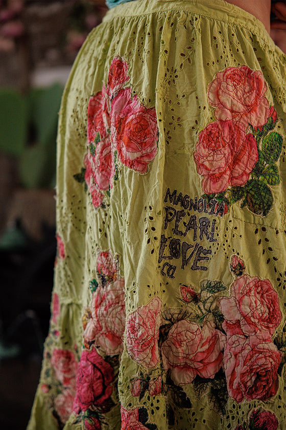 Yellow dress with pink floral embroidery and text on a blurred background