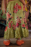 Person wearing a yellow floral skirt with pink roses in an indoor setting.