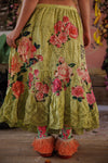 Person wearing a yellow floral skirt with pink roses on a wooden floor.