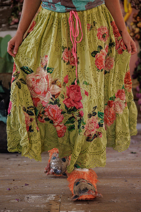 Person wearing a floral skirt with a wooden floor background
