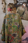Person wearing a colorful, patterned jacket with text in an artistic setting.