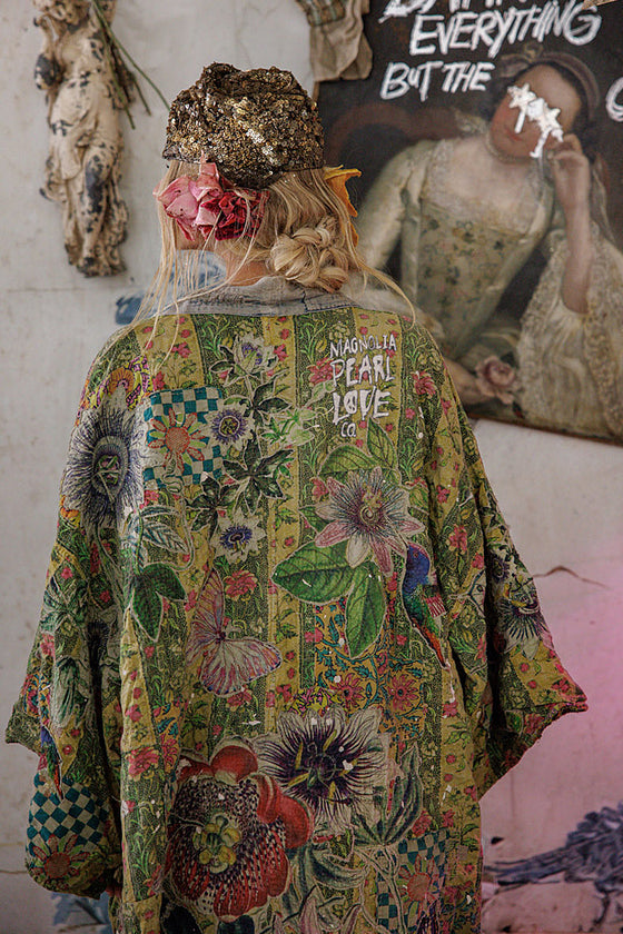 Person wearing a colorful, patterned jacket with text in an artistic setting.