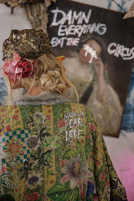 Person wearing a colorful jacket with text, standing in front of a poster with text.