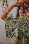 Person wearing a colorful floral dress with a blurred background