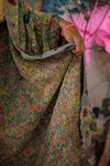 Person wearing a colorful floral dress with a blurred background