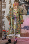 Person wearing a colorful, patterned outfit in a room with artistic decor.