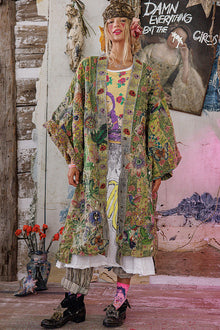  Person wearing a colorful, patterned outfit in a room with artistic decor.
