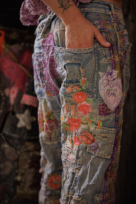Close-up of a person wearing jeans with floral and heart patches.