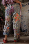 Person wearing patchwork pants with floral patterns in a rustic setting