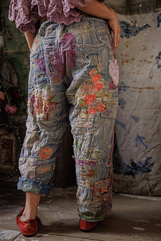 Person wearing patchwork pants with floral patterns in a rustic setting