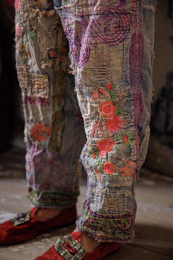 Patchwork pants with floral embroidery and red shoes on a blurred background
