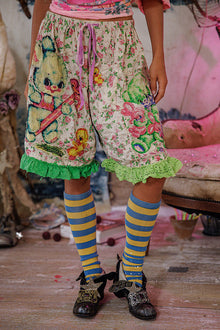  Person wearing floral shorts with teddy bear design and colorful socks in a casual setting.