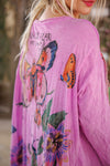Pink dress with butterfly and floral designs on a blurred natural background