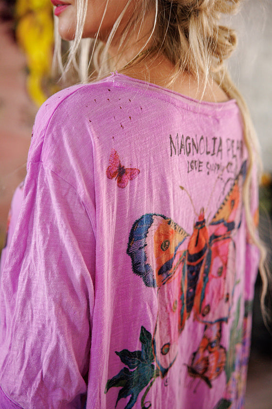 Pink dress with butterfly designs and text on the back, worn by a person.