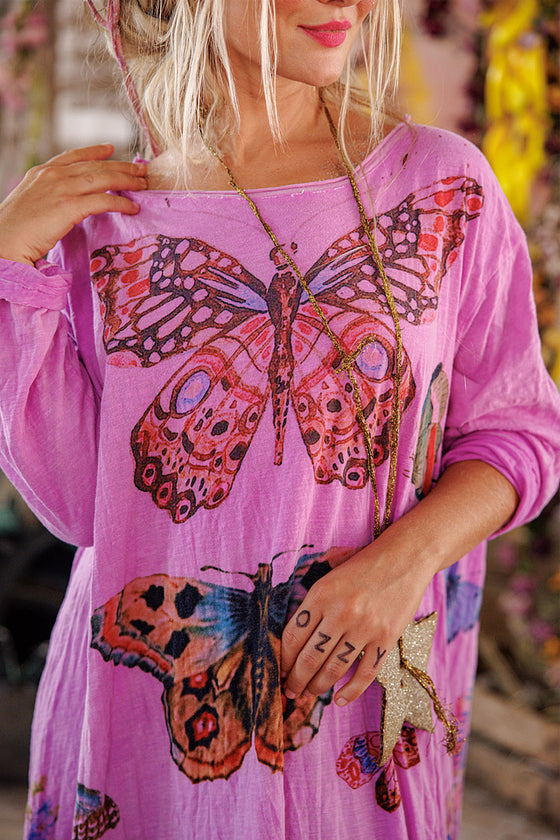 Woman wearing a pink dress with butterfly designs.