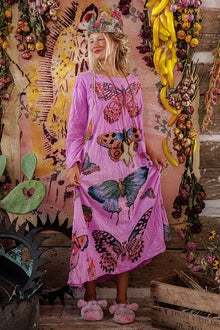  Woman wearing a pink dress with butterfly designs in a decorative setting.