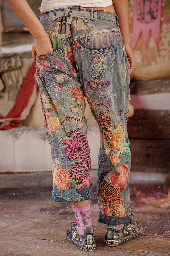 Person wearing colorful patchwork pants with animal designs in a casual setting.