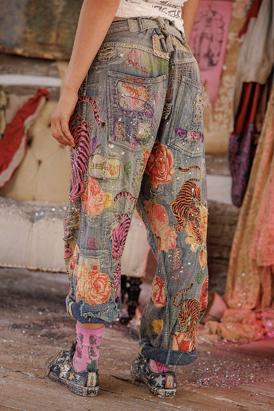 Colorful patchwork pants with floral and animal patterns worn by a person.