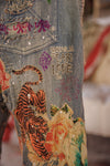 Close-up of a denim jacket with embroidered tiger design and text.