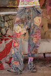 Person wearing floral patchwork jeans in a room with furniture and decor.