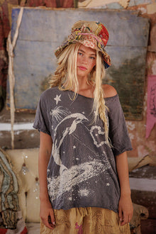  Woman wearing a graphic t-shirt with a dolphin design in a rustic setting