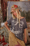 Woman wearing a graphic t-shirt and colorful hat in a rustic setting