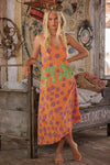 Woman wearing an orange dress with colorful text in a rustic setting