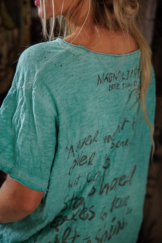 Person wearing a teal t-shirt with text on the back