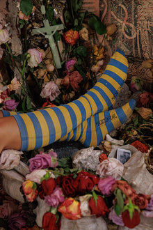  Person wearing blue and yellow striped socks with flowers and a cross in the background