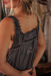 Woman wearing a gray sleeveless dress with lace details, blurred background
