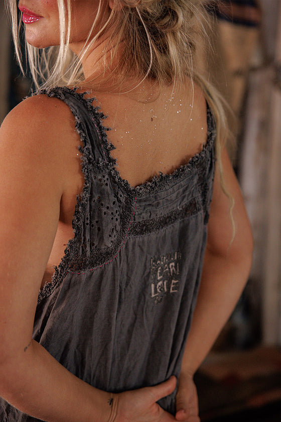 Woman wearing a gray sleeveless dress with lace details, blurred background
