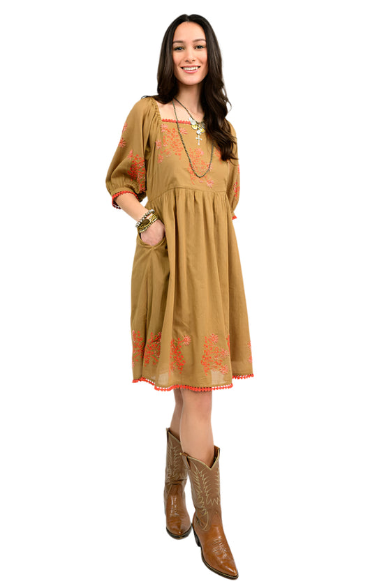 Woman wearing a copper dress with coral  floral embroidery on a white background