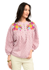 Woman wearing a pink blouse with floral embroidery on a white background